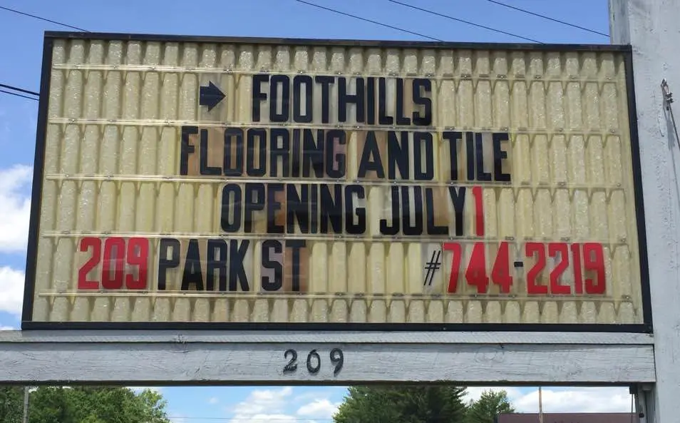 image - 2025-03-13T153349.737 image shows a sign for Foothills Flooring and Tile, announcing its opening on July 1st, at 209 Park St, with the phone number 744-2219