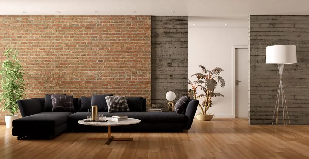 image (96) modern living room interior with a black sectional sofa, a round marble coffee table, and a mix of textures on the walls, including exposed brick and concrete panels